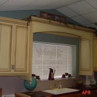 Kitchen cabinets and sink beneath a window with blinds, under a slanted ceiling, with a globe on the counter.