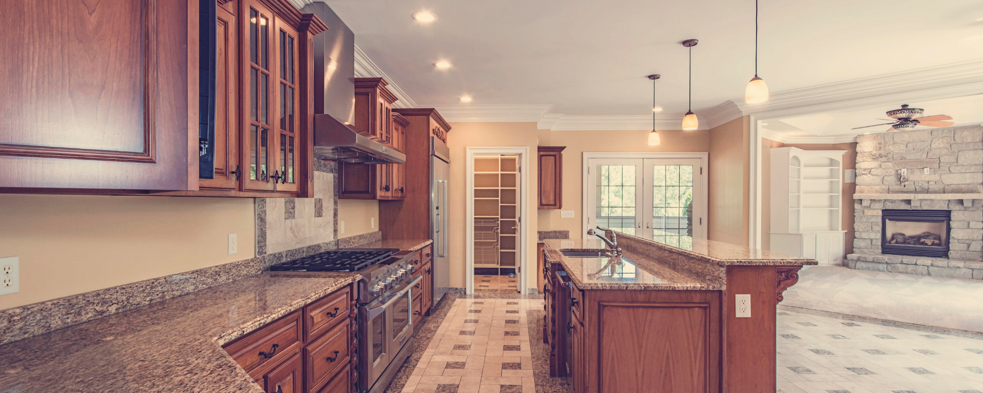 Modern kitchen with wood cabinets, granite island, and tiled floor leading to a bright breakfast nook