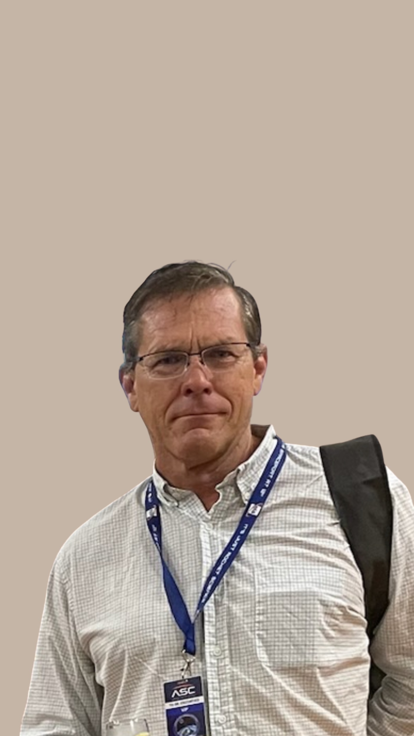 A man with glasses and a beard, wearing a blue shirt, looking at the camera.