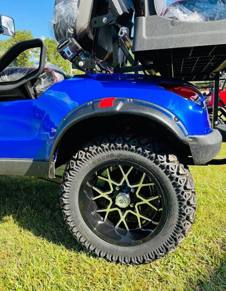 A blue golf cart with black wheels and tires is parked in the grass.