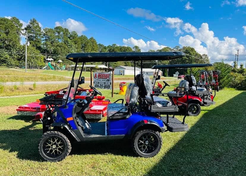 A row of golf carts are parked in a grassy field.