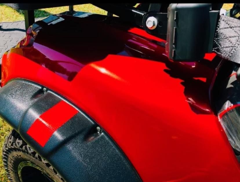 A red golf cart with black fender flares and a red stripe on the side