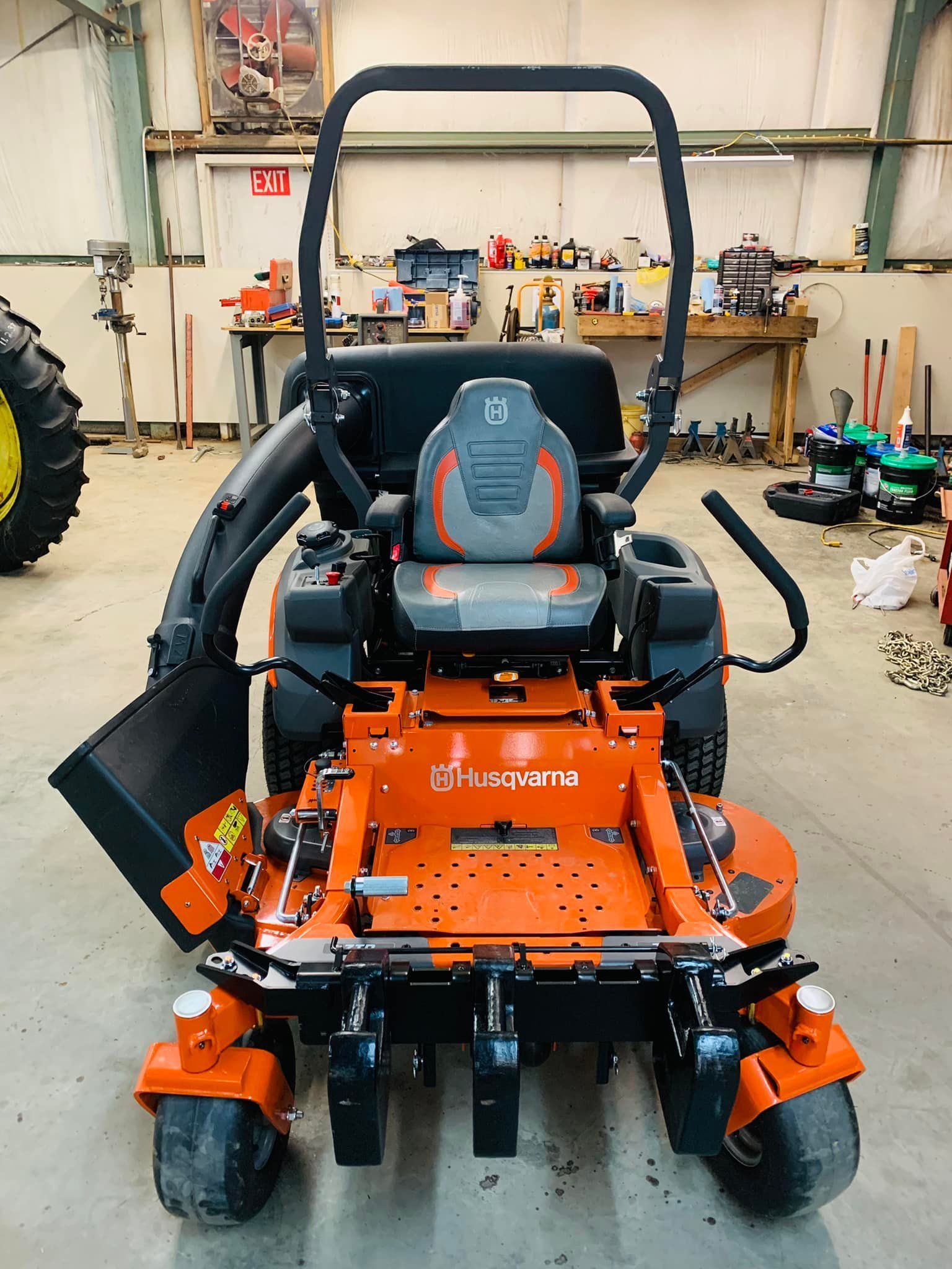An orange and black lawn mower is parked in a garage.