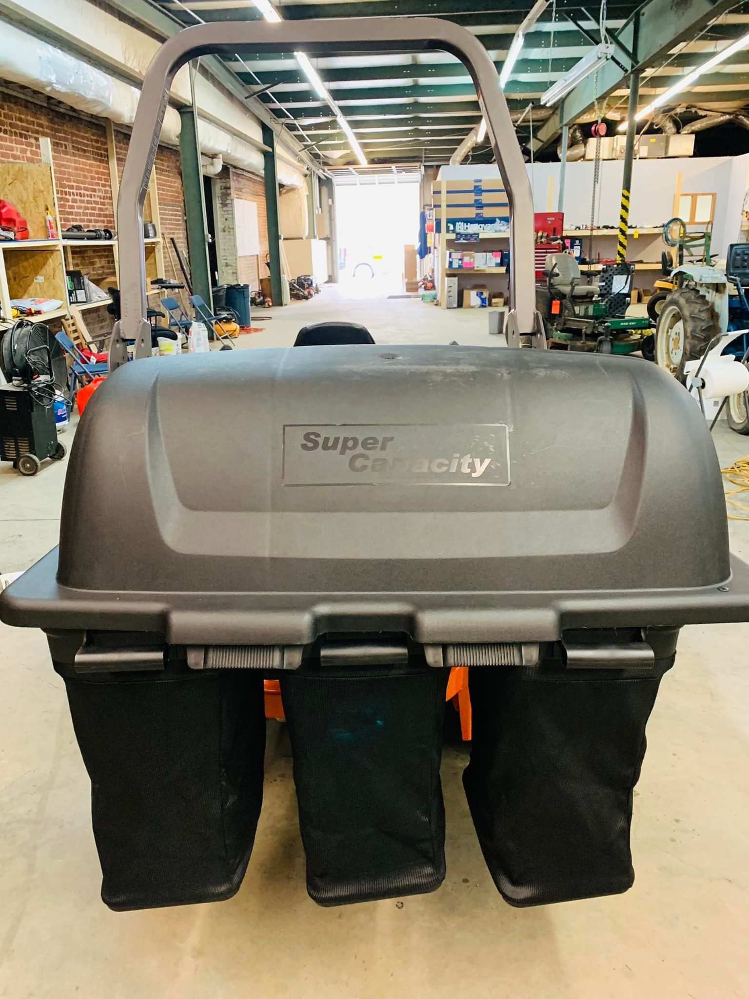 A black lawn mower is sitting in a warehouse.