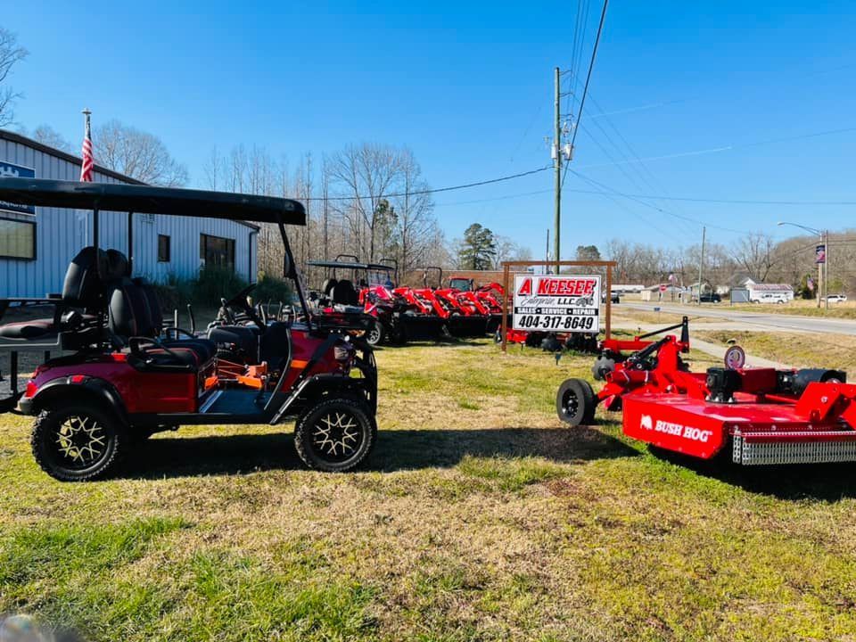 A golf cart is parked next to a lawn mower in a grassy field.