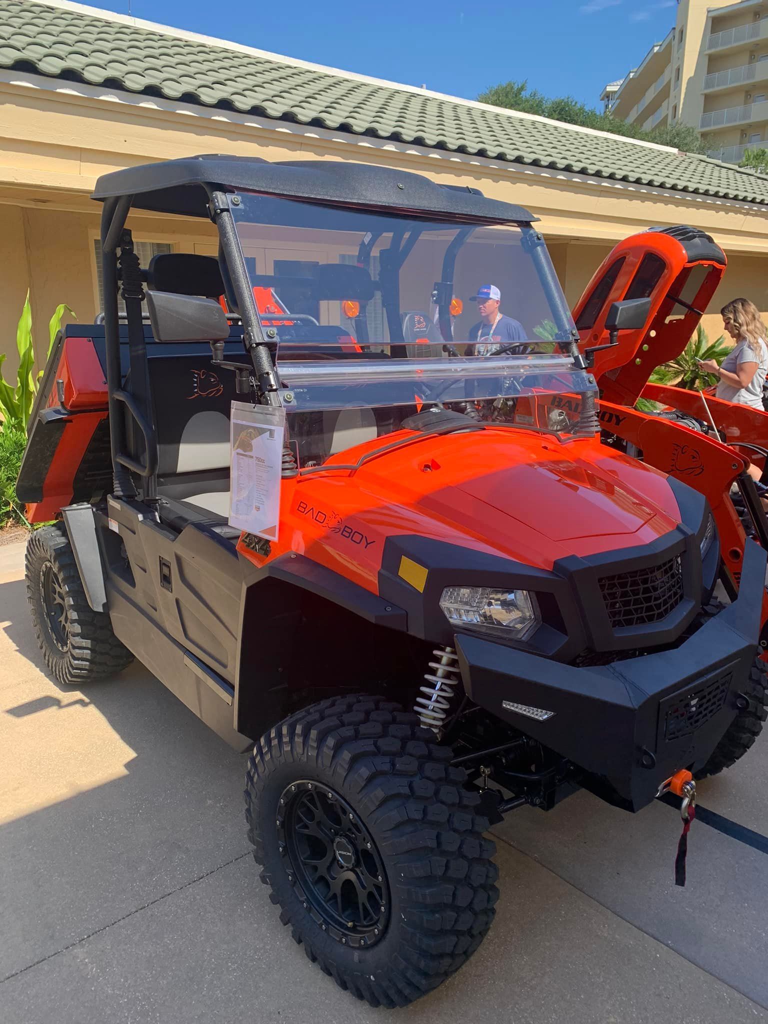 A red atv with the hood up is parked in front of a building.