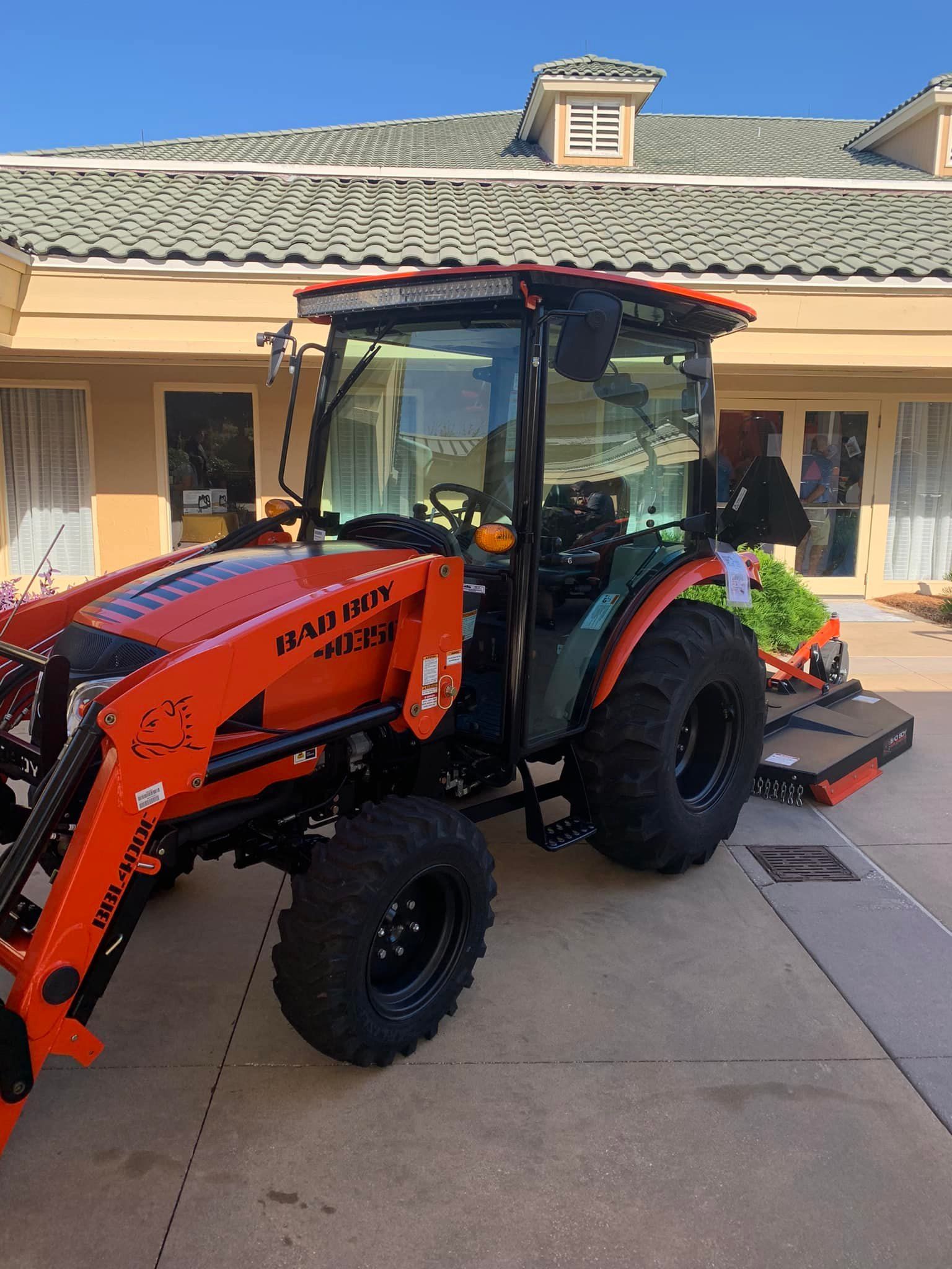 An orange tractor is parked in front of a building.