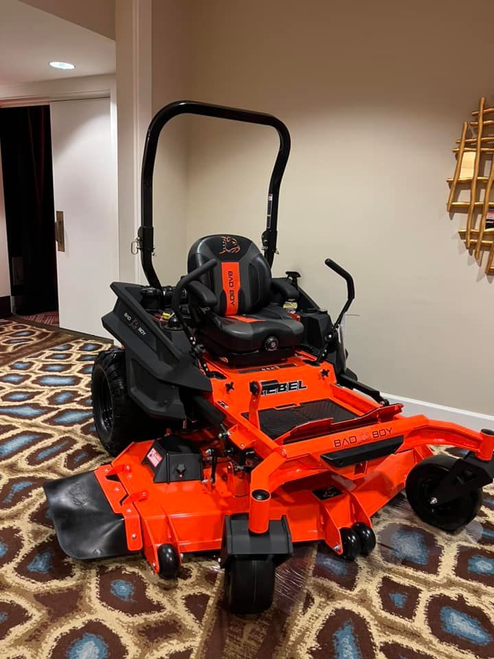 An orange lawn mower is parked on a rug in a room.