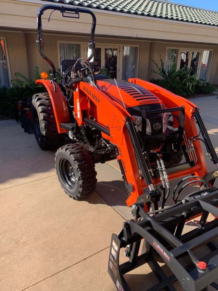 An orange tractor is parked in front of a building.