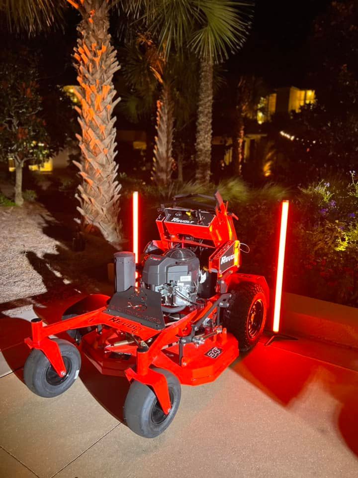 A red lawn mower is parked on a sidewalk at night.