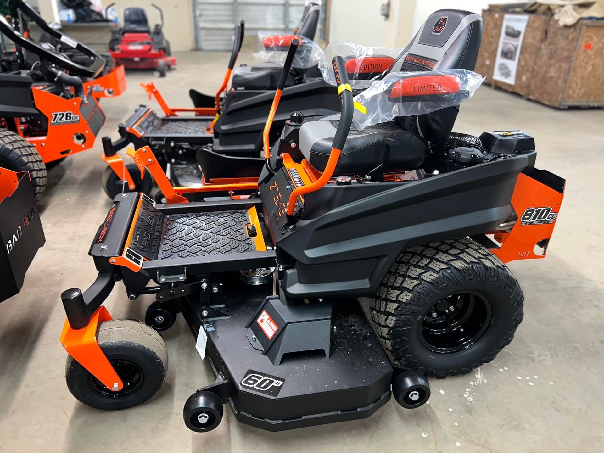 A row of lawn mowers are lined up in a warehouse.