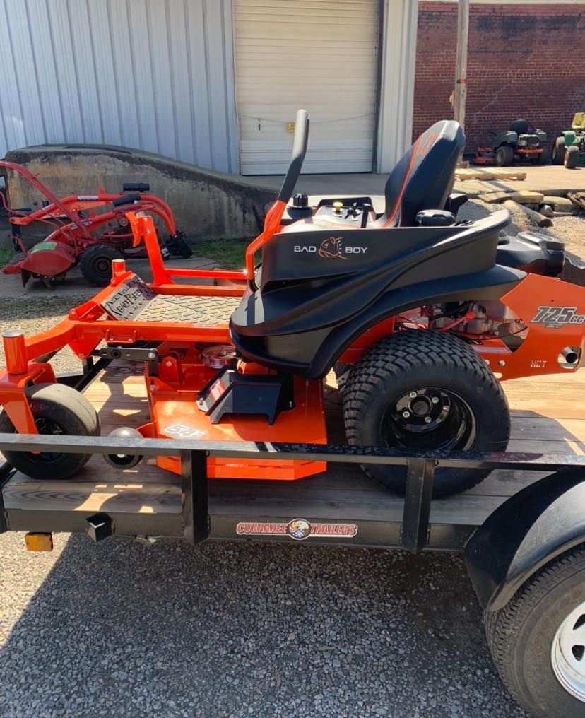An orange and black lawn mower is on a trailer.