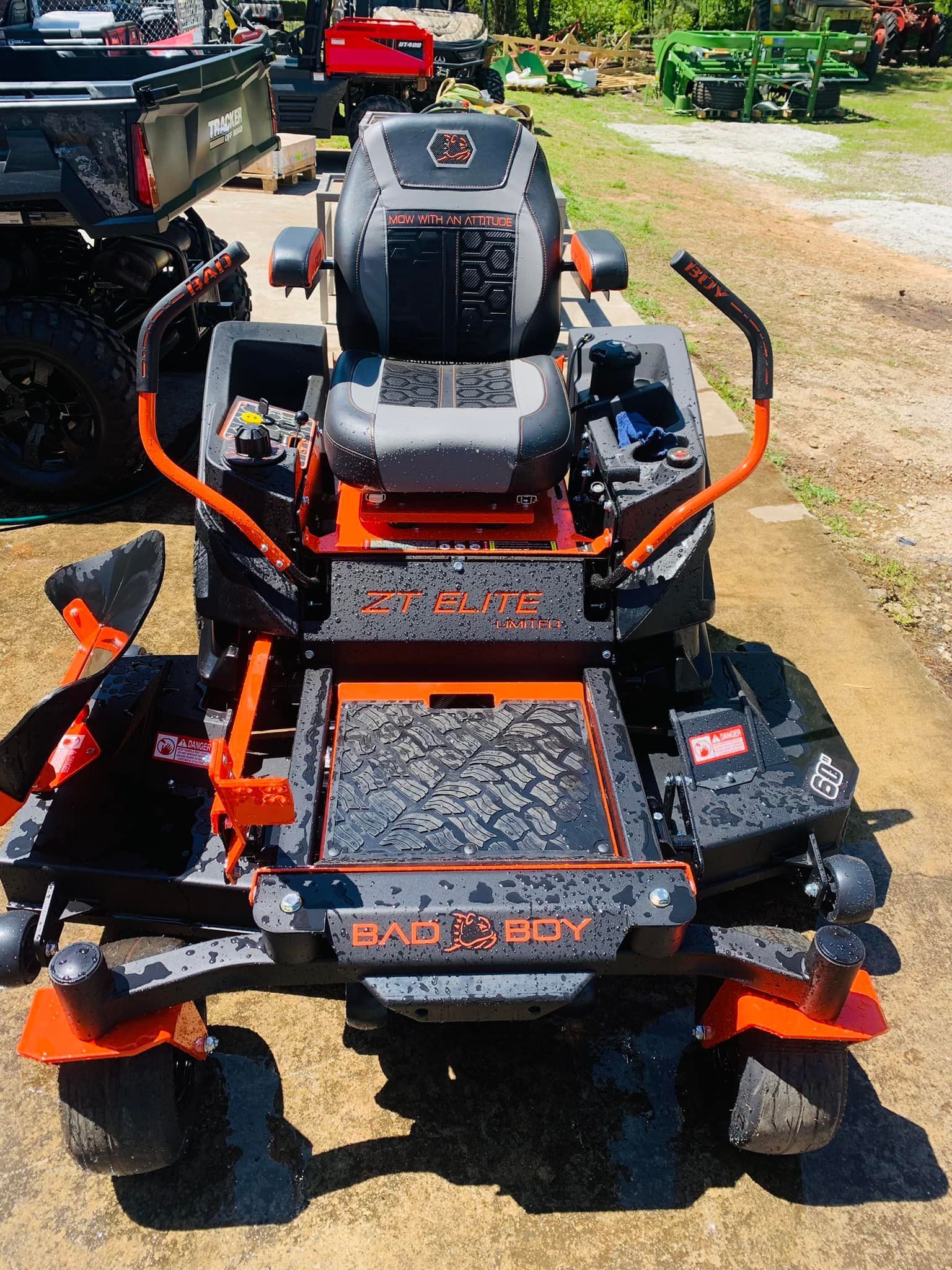 A black and orange lawn mower is parked in a field.