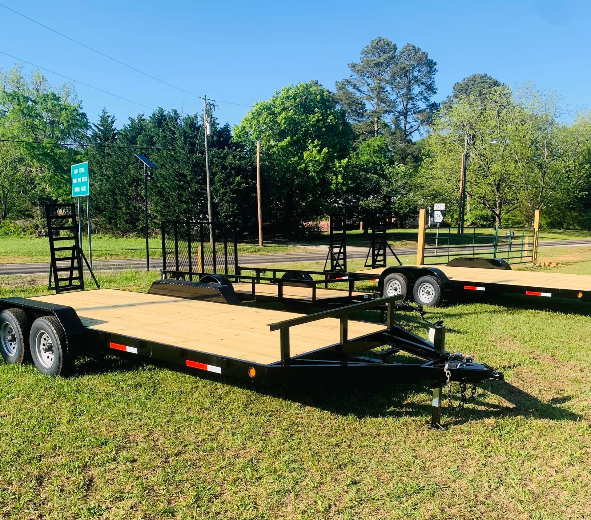 Three trailers are parked in a grassy field.