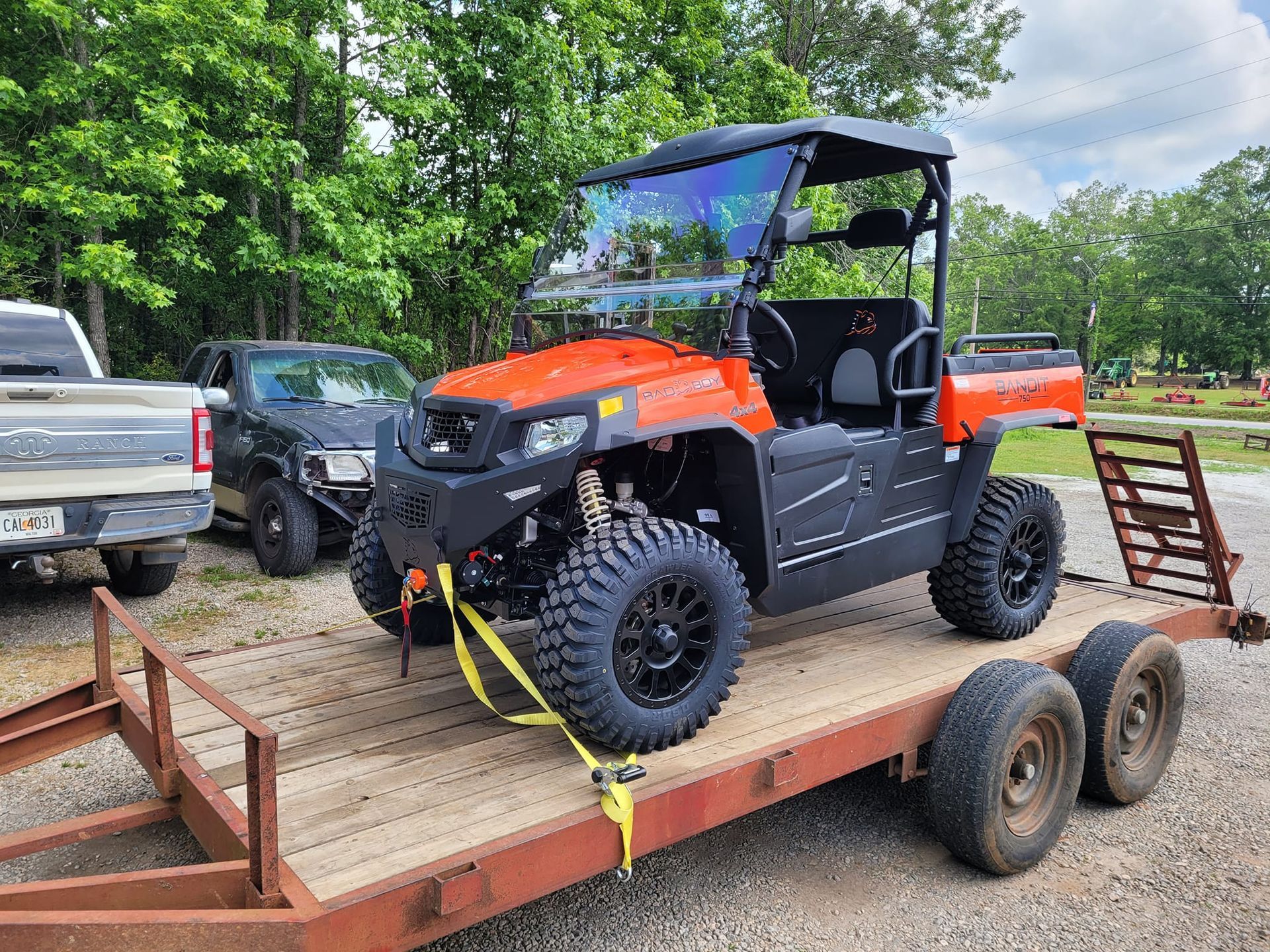 An orange and black atv is sitting on top of a trailer.