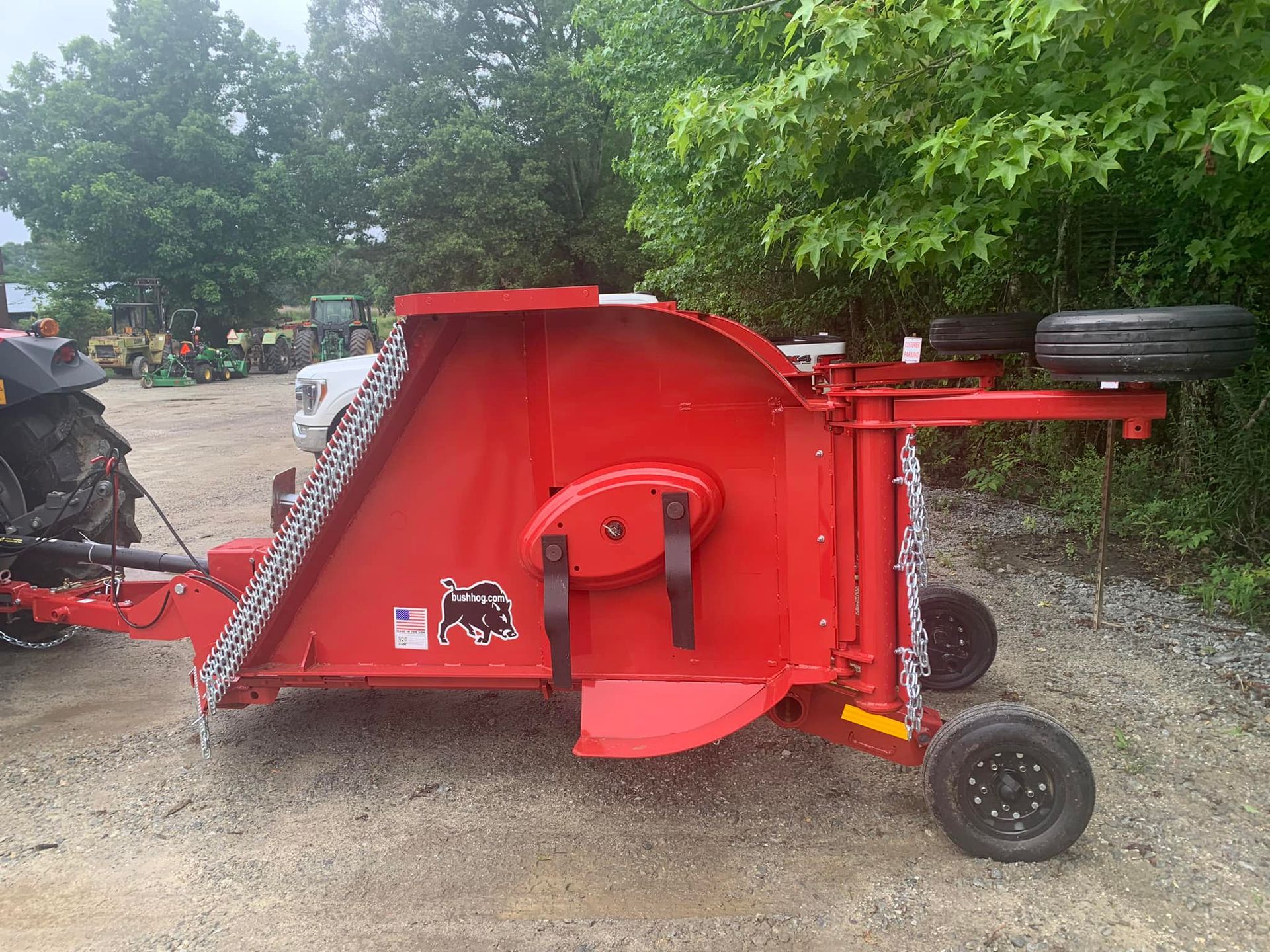 A red lawn mower is parked next to a tractor.