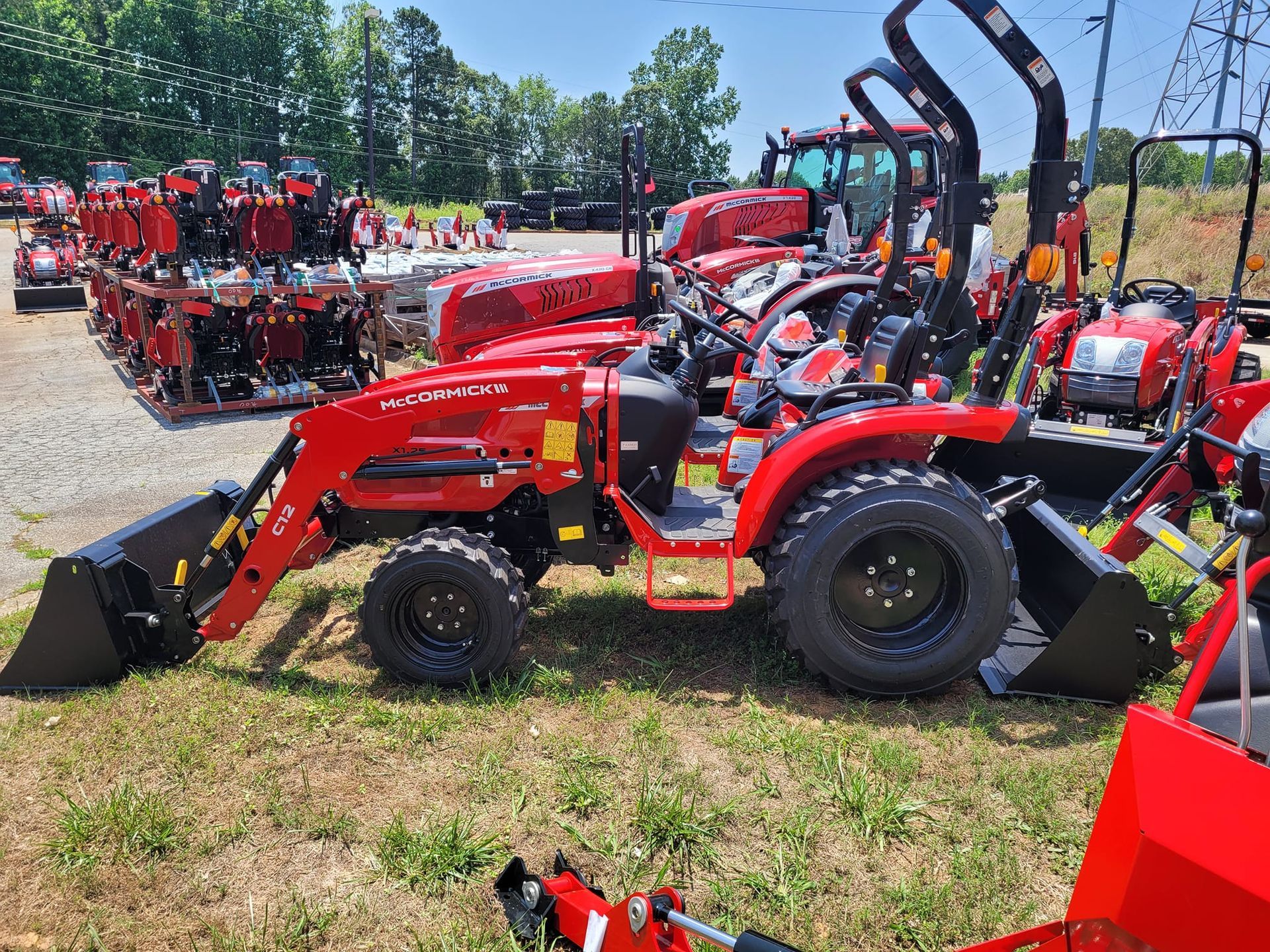 A row of red tractors are parked in a grassy field.