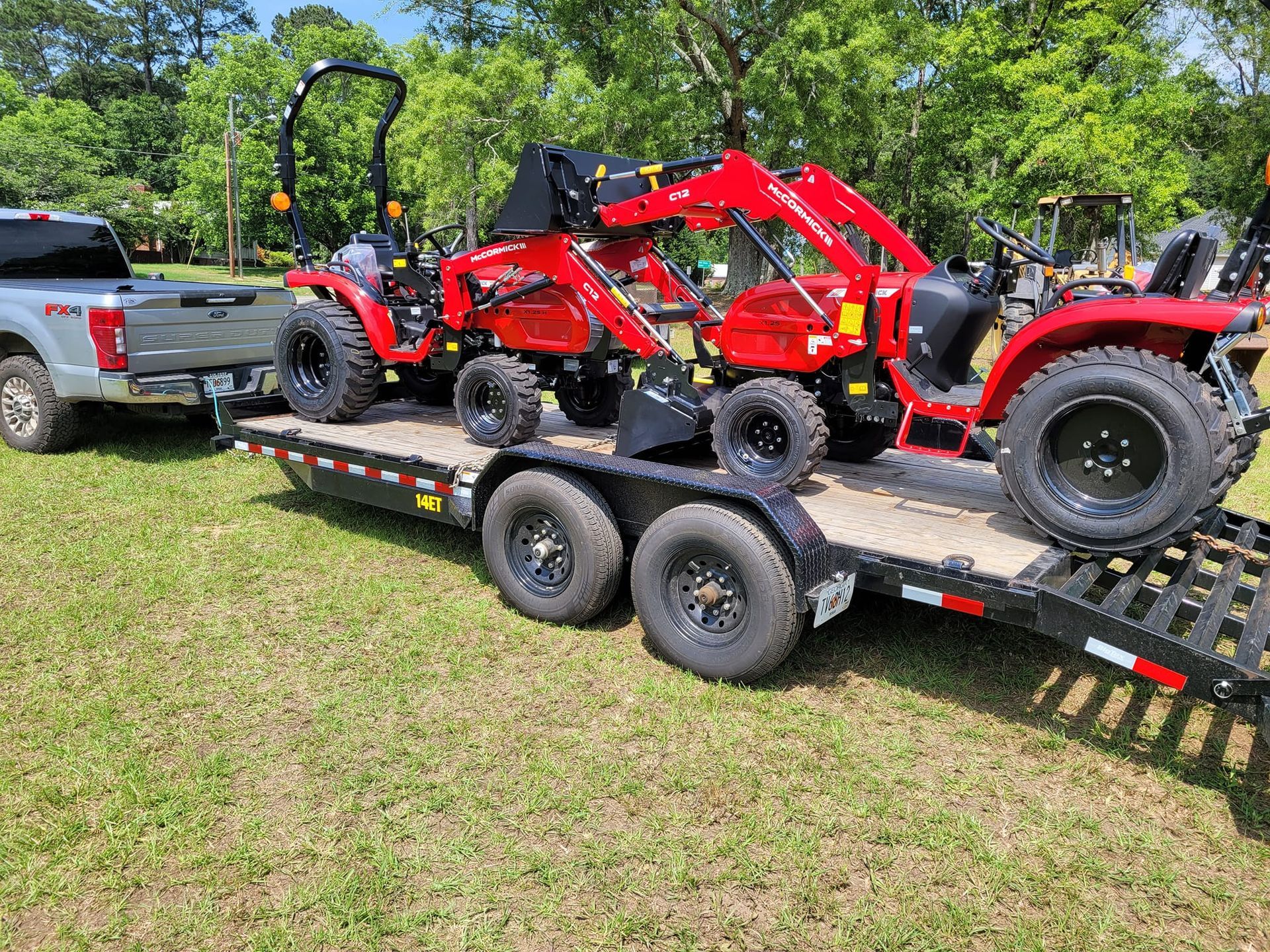 A truck is towing a trailer with two tractors on it.