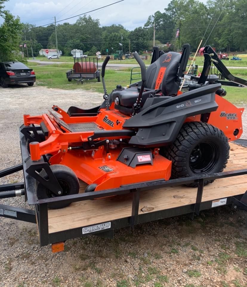 An orange and black lawn mower is on a trailer