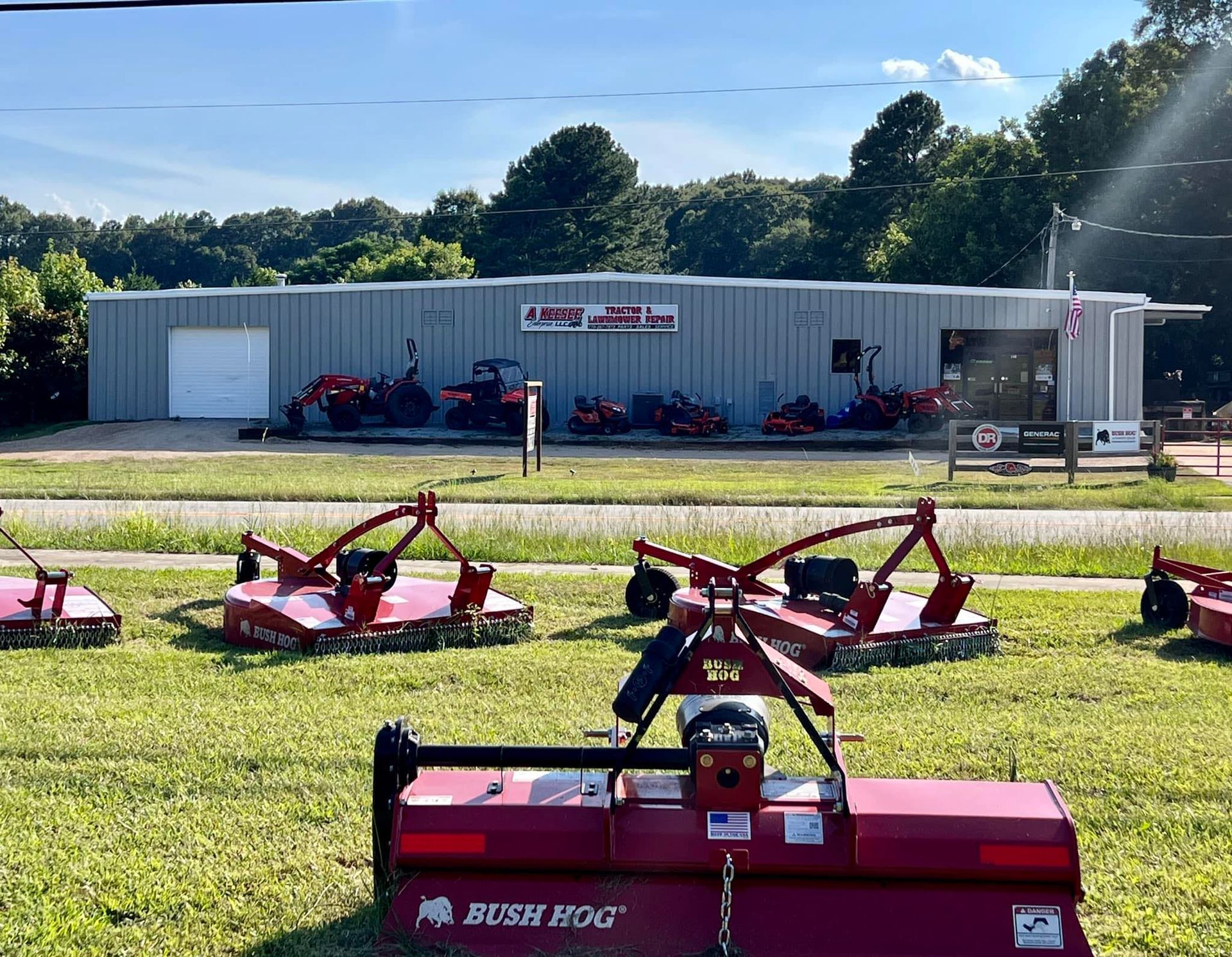 A bush hog lawn mower is sitting in front of a building
