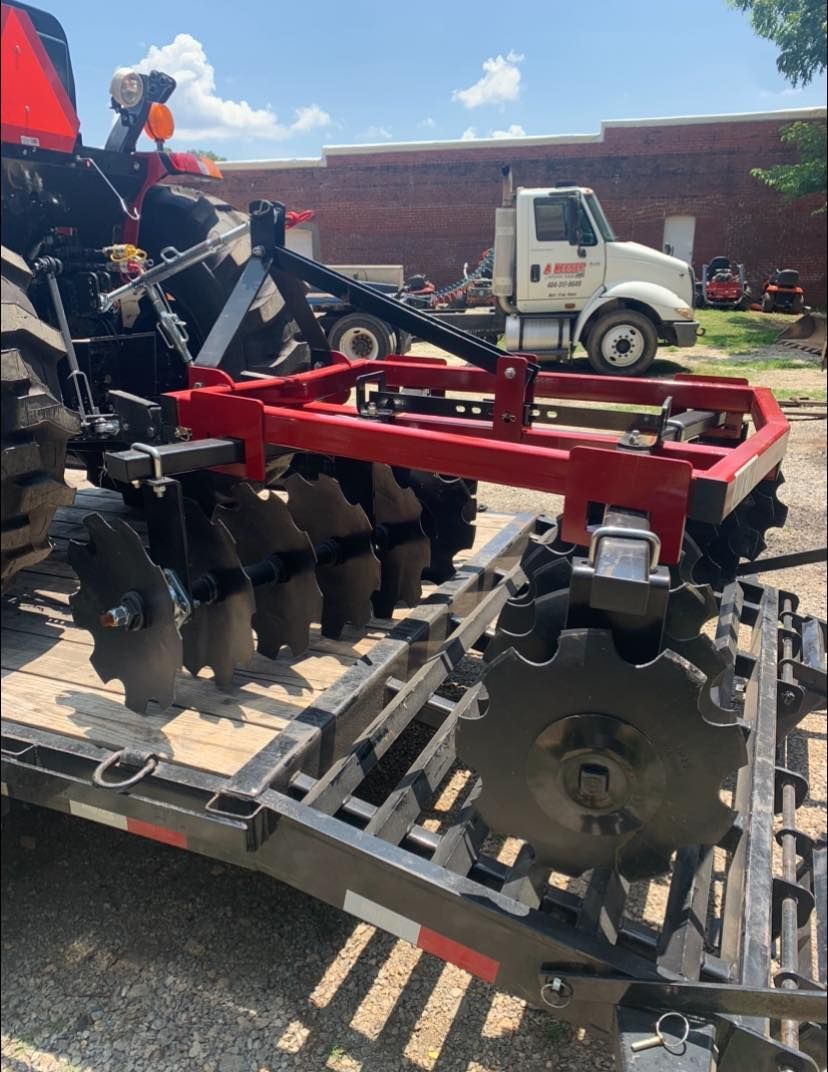 A tractor is being towed by a trailer with a plow attached to it.