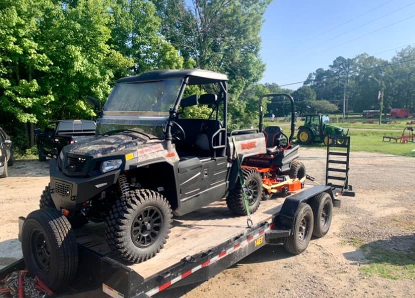 A utility vehicle is sitting on top of a trailer.