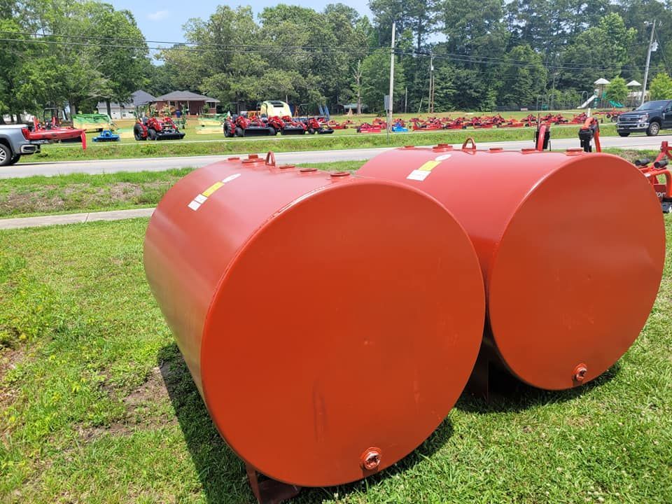 Two red barrels are sitting on top of a lush green field.