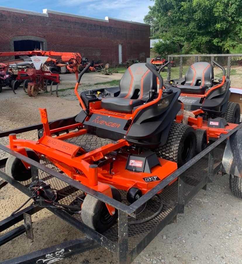 A row of orange and black lawn mowers on a trailer