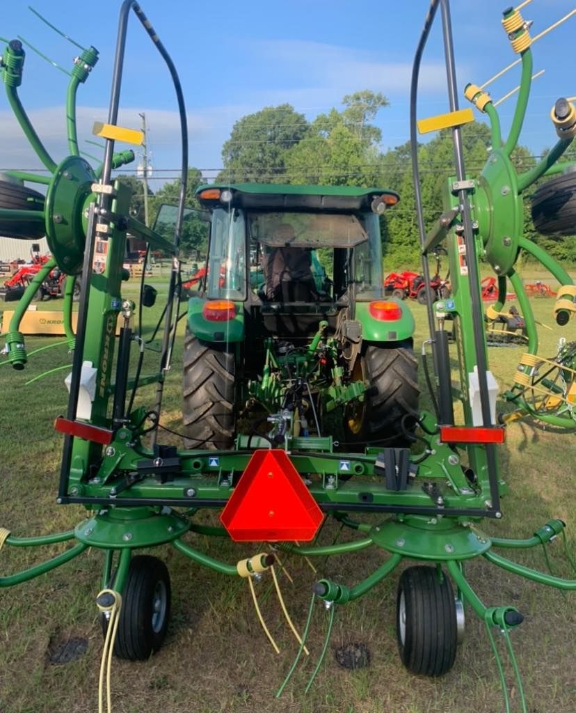A green tractor with a red sign on the back is parked in a field.