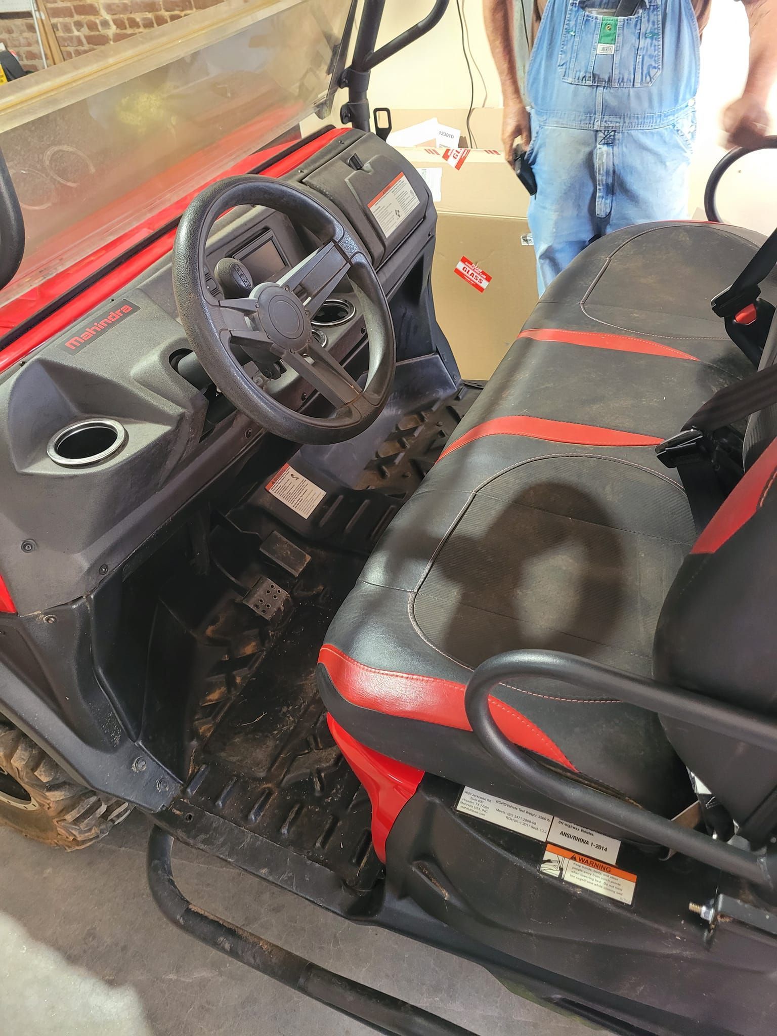 A man in overalls is standing next to a snowmobile.
