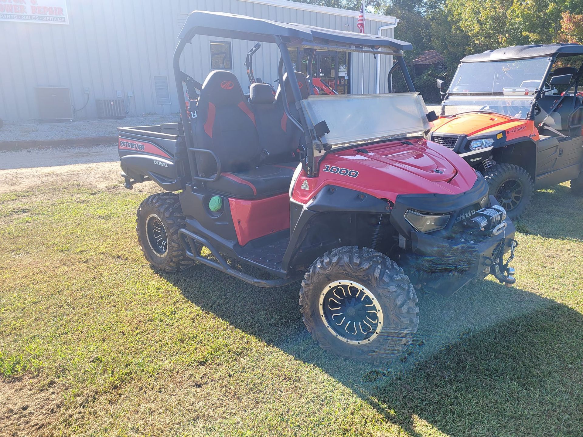 A red atv is parked in the grass in front of a building.