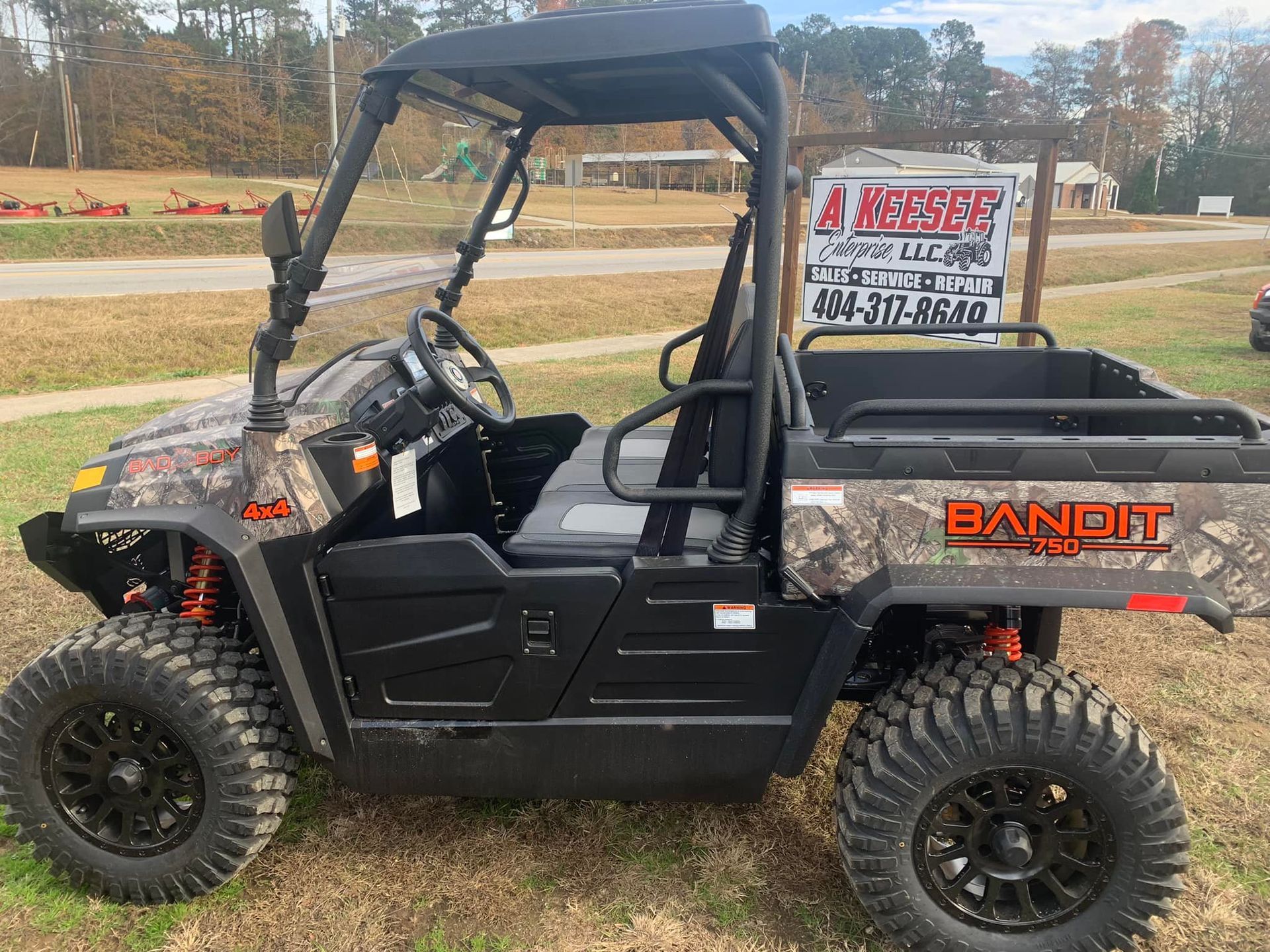 A camouflage atv is parked in the grass next to a sign.