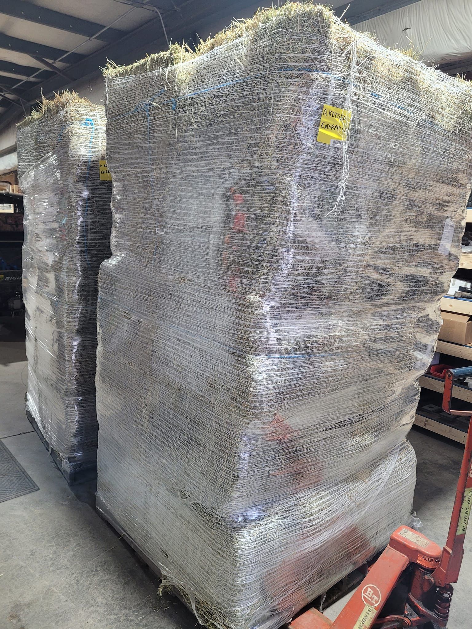 A pallet of hay is sitting on top of a pallet in a warehouse.