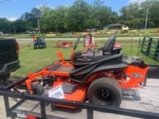 An orange lawn mower is sitting on top of a trailer.