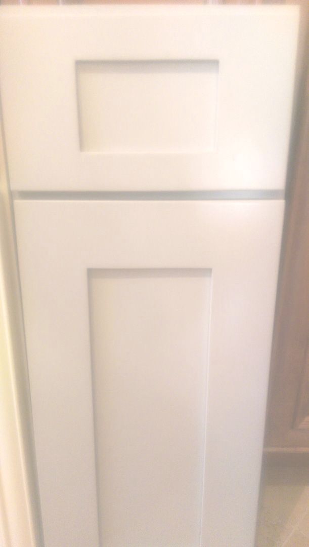 A white cabinet is sitting in a room next to a door.