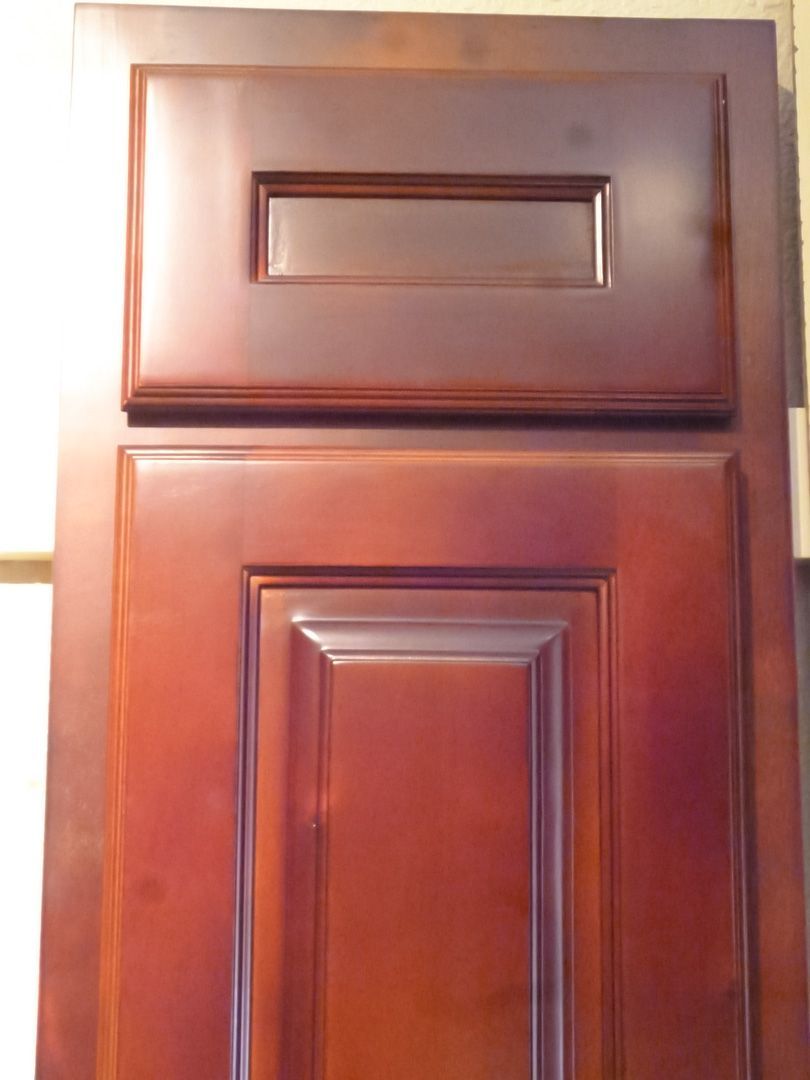 A close up of a wooden cabinet door with a drawer underneath it