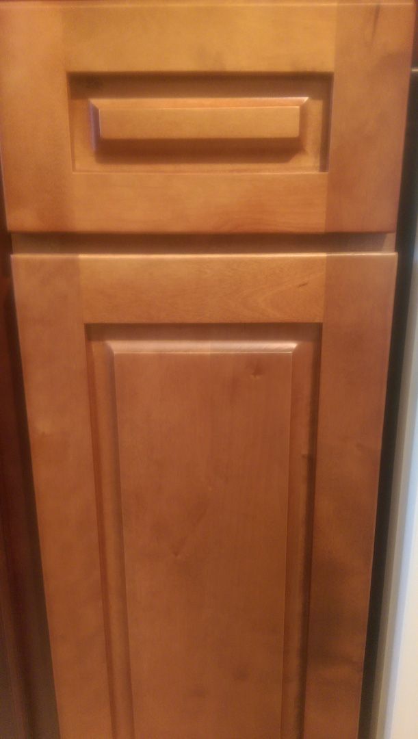 A close up of a cinnamon maple wooden cabinet door in a kitchen.