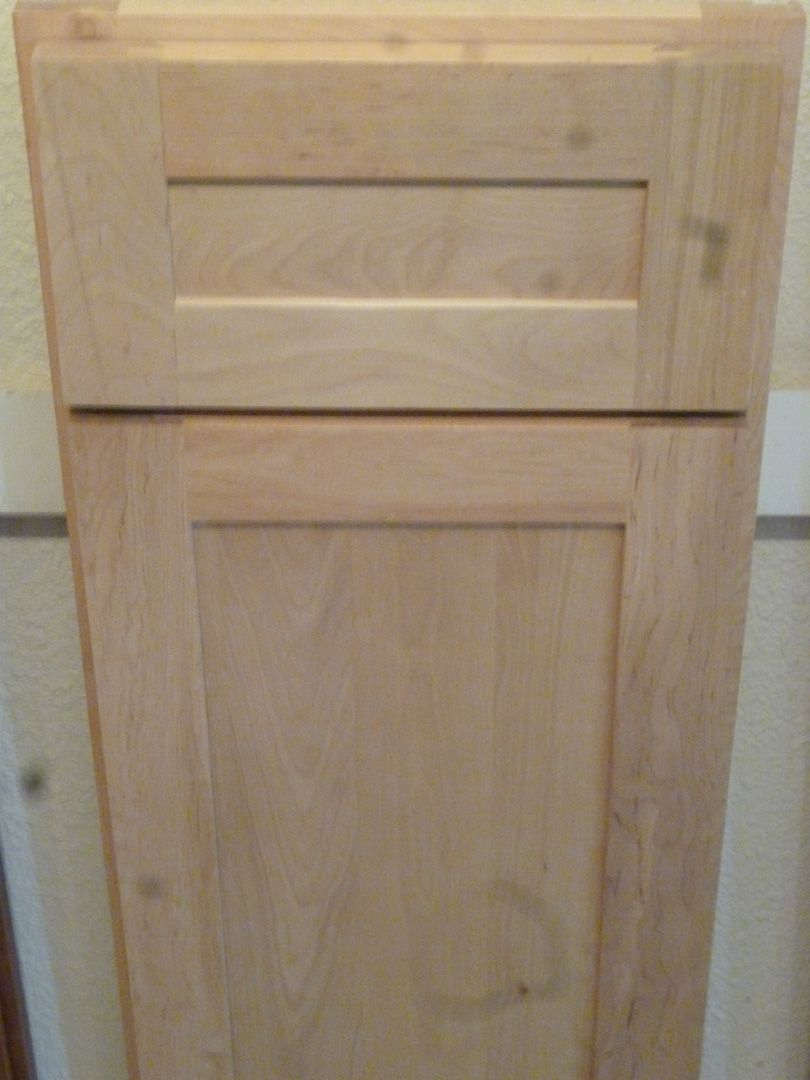 A wooden cabinet door with a drawer underneath it.