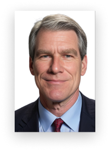 A man in a suit and tie is smiling for the camera