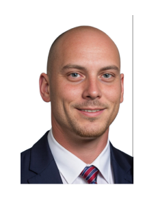 A man in a suit and tie is smiling for the camera