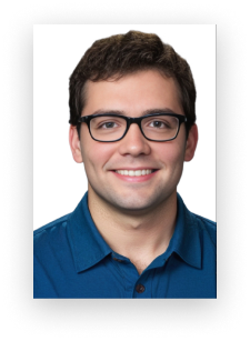 A man wearing glasses and a blue shirt smiles for the camera
