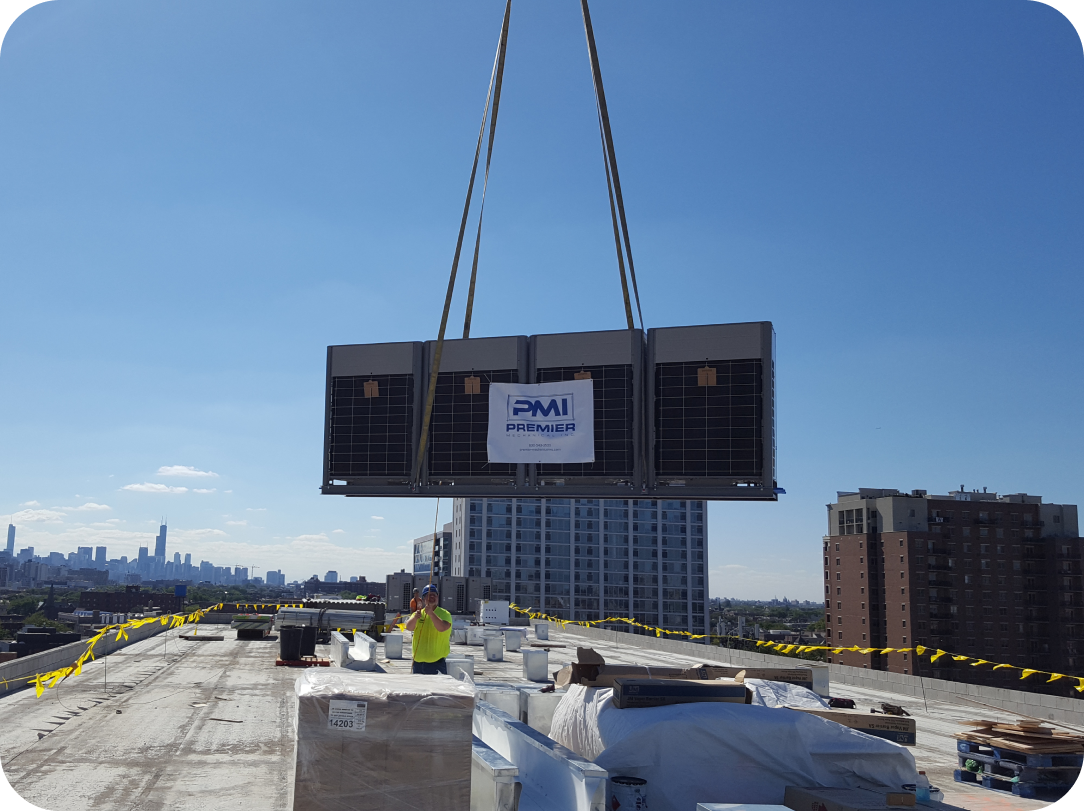 A crane is lifting an air conditioner on top of a building