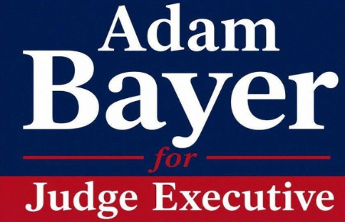 Campaign sign reading “Adam Bayer for Judge Executive” in white text on a blue and red background