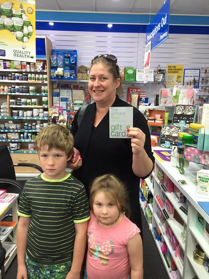 Woman holding a card in a store aisle with two children standing in front of her