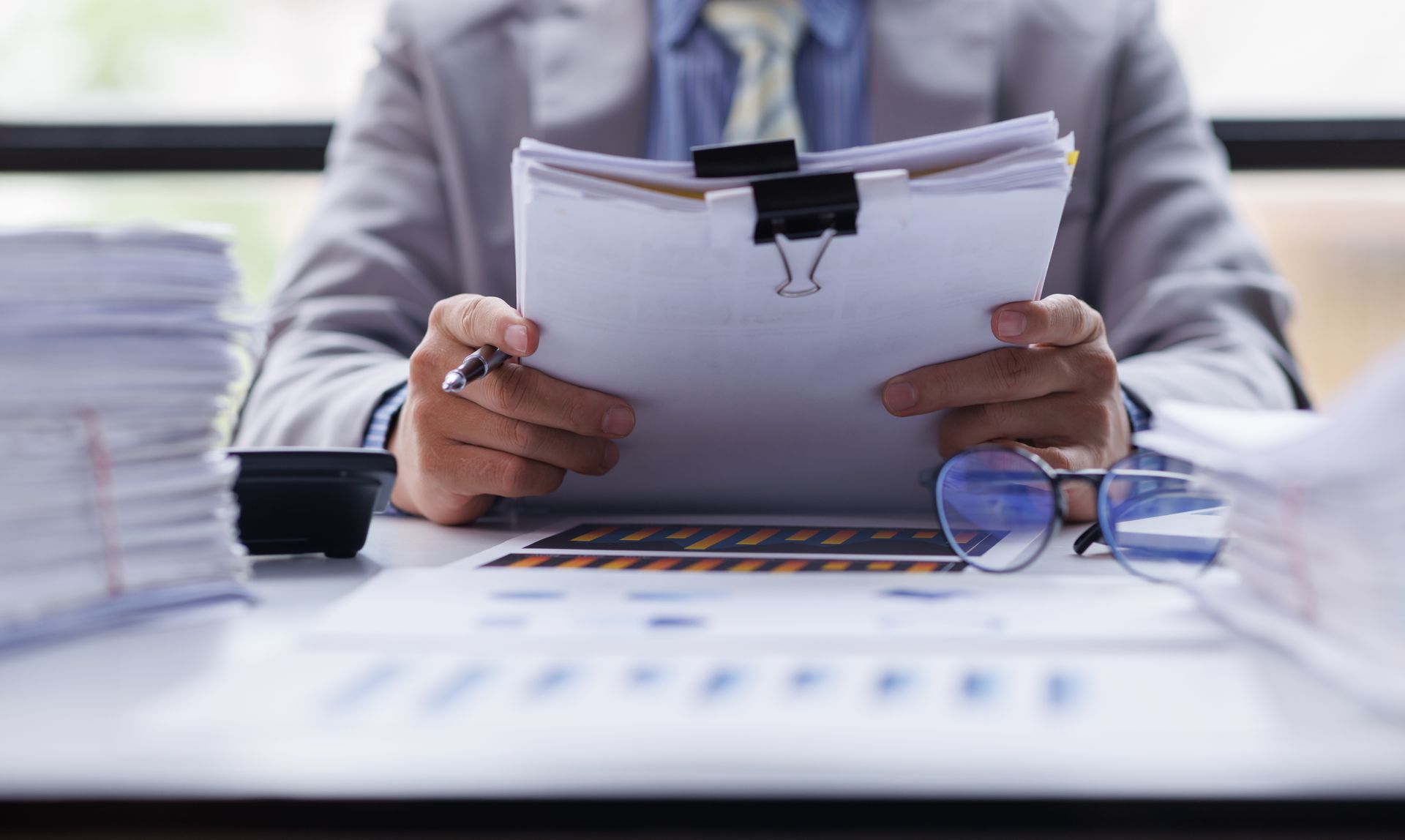 Person in a suit reviews papers at a desk