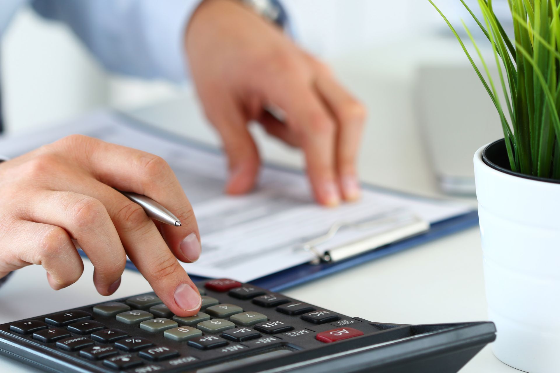 Person's hands using a calculator over a document