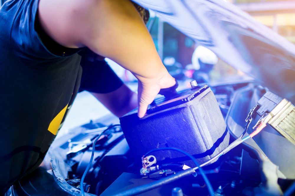 A Person Is Plugging a Battery Into a Car — BEB Automotive In Albion Park, NSW