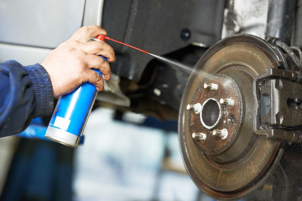 A Person Is Cleaning a Brake Disc with A Spray Can — BEB Automotive In Nowra, NSW