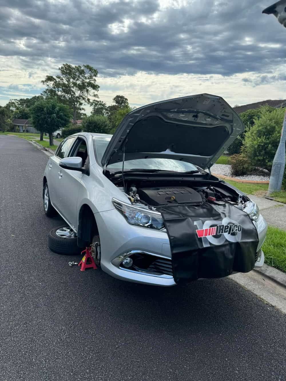 A Silver Car with The Hood up Is Sitting on The Side of The Road — BEB Automotive In Berkeley, NSW
