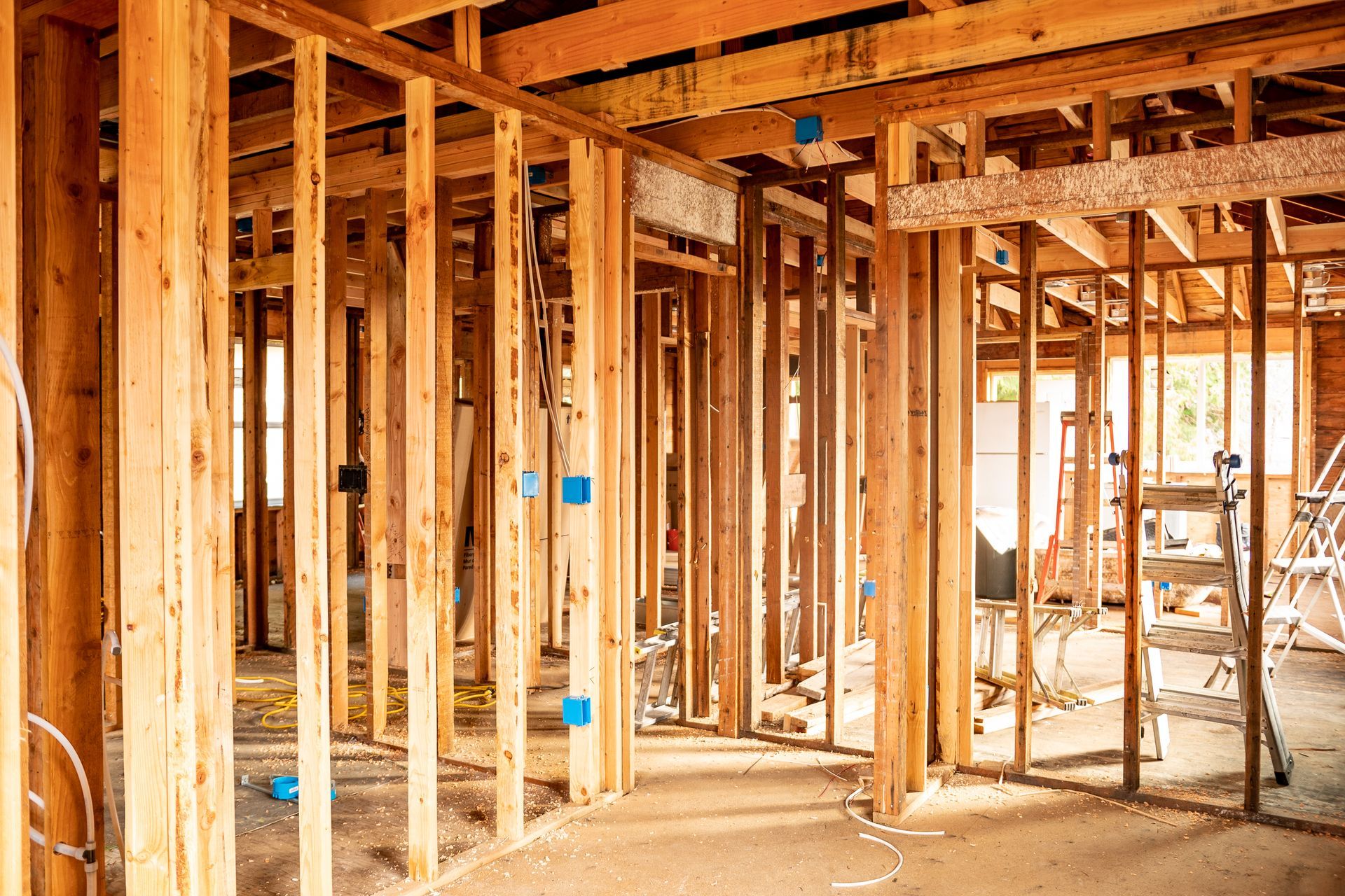 The inside of a house under construction with wooden beams and a ladder.